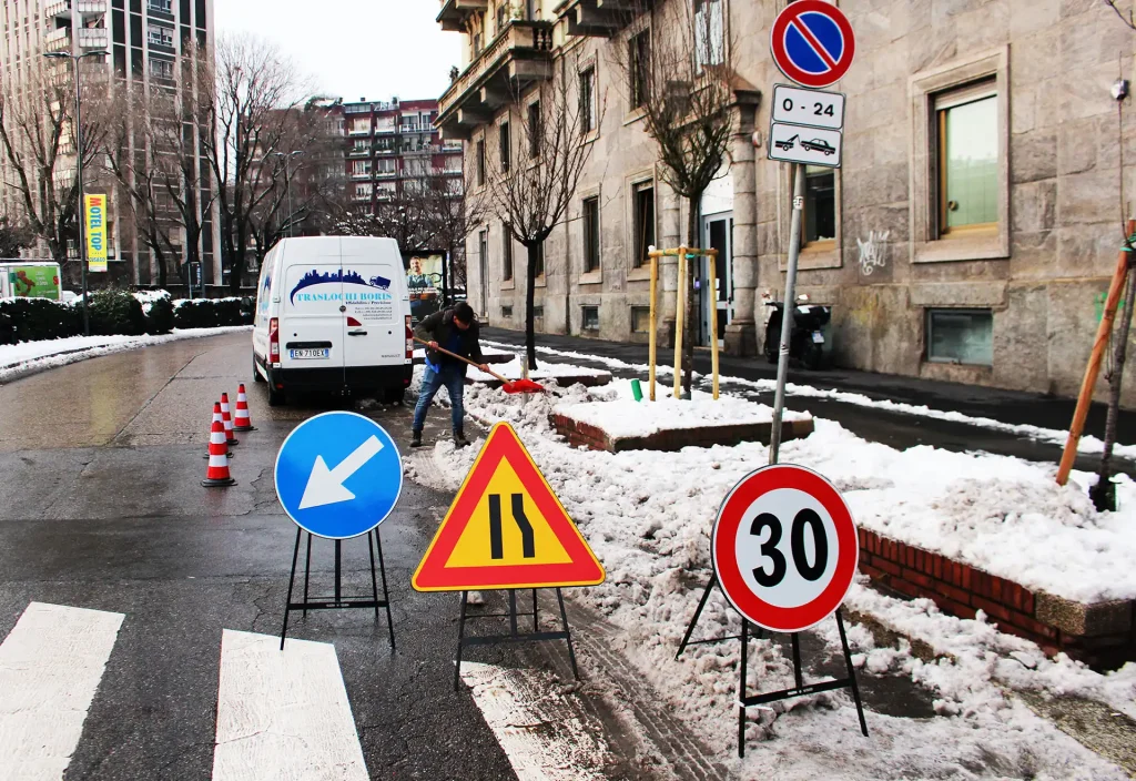 Operatore di Traslochi Boris prepara l'area con segnaletica stradale per l'occupazione del suolo pubblico in una zona innevata.